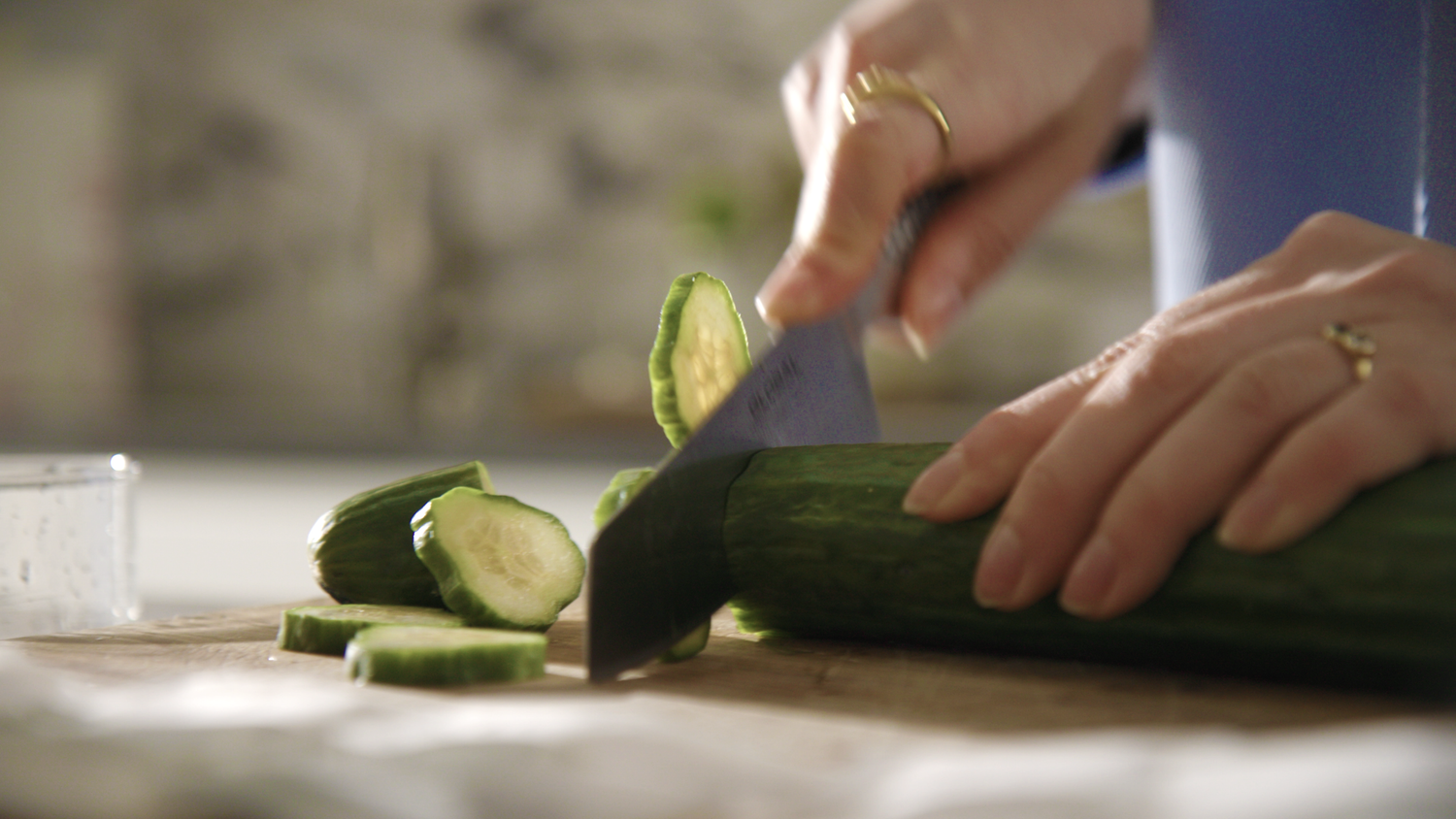 Chopping cucumber on wooden chopping board 